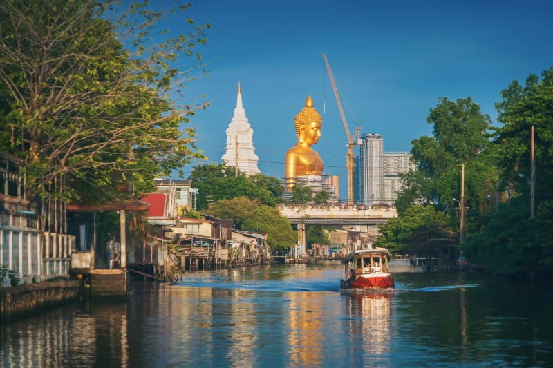 The Giant Golden Buddha in Wat Paknam Phasi Charoen Temple in Phasi Charoen district with boat on Chao Phraya River, Bangkok urban city, Thailand.